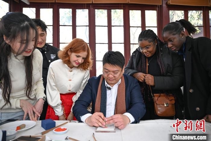 1月20日，篆刻家王臻向外籍留學(xué)生展示篆刻印章。當日，來自巴西、馬來西亞、加納、哈薩克斯坦的外籍留學(xué)生在浙江杭州西泠印社體驗福貼、春聯(lián)和篆刻，感受古老的中國傳統(tǒng)文化。中新社記者 王剛 攝