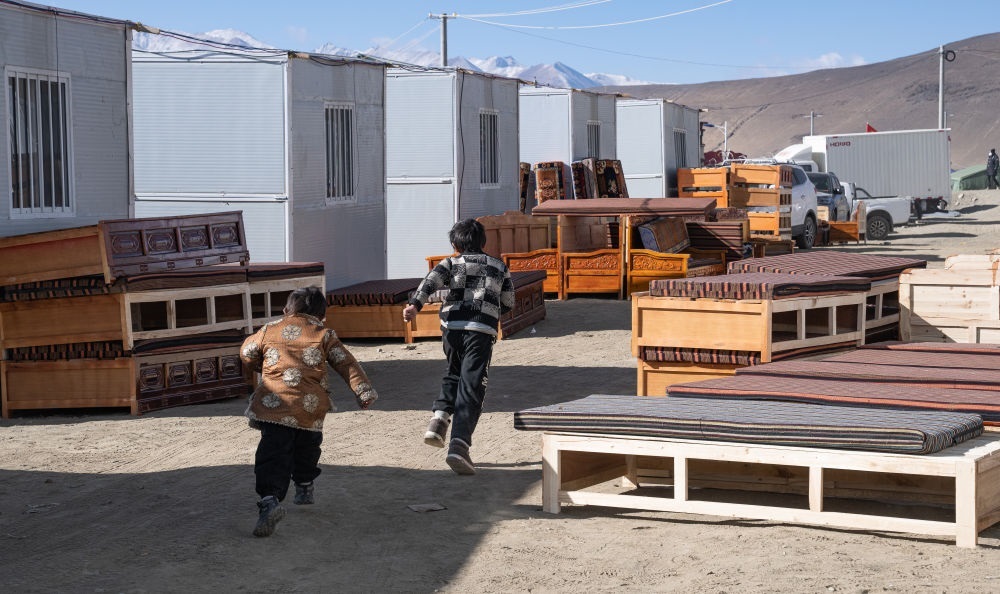 2025年1月13日，在定日縣嘎旦村，兩個(gè)孩子在剛運(yùn)來的兩排藏床間奔跑。新華社記者丁增尼達(dá) 攝