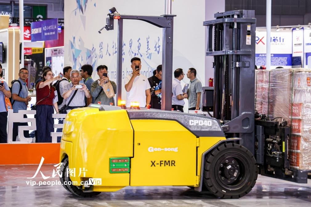 第24屆中國工博會現(xiàn)場，觀眾觀看叉取機器人作業(yè)演示。王初攝（人民圖片網(wǎng)）