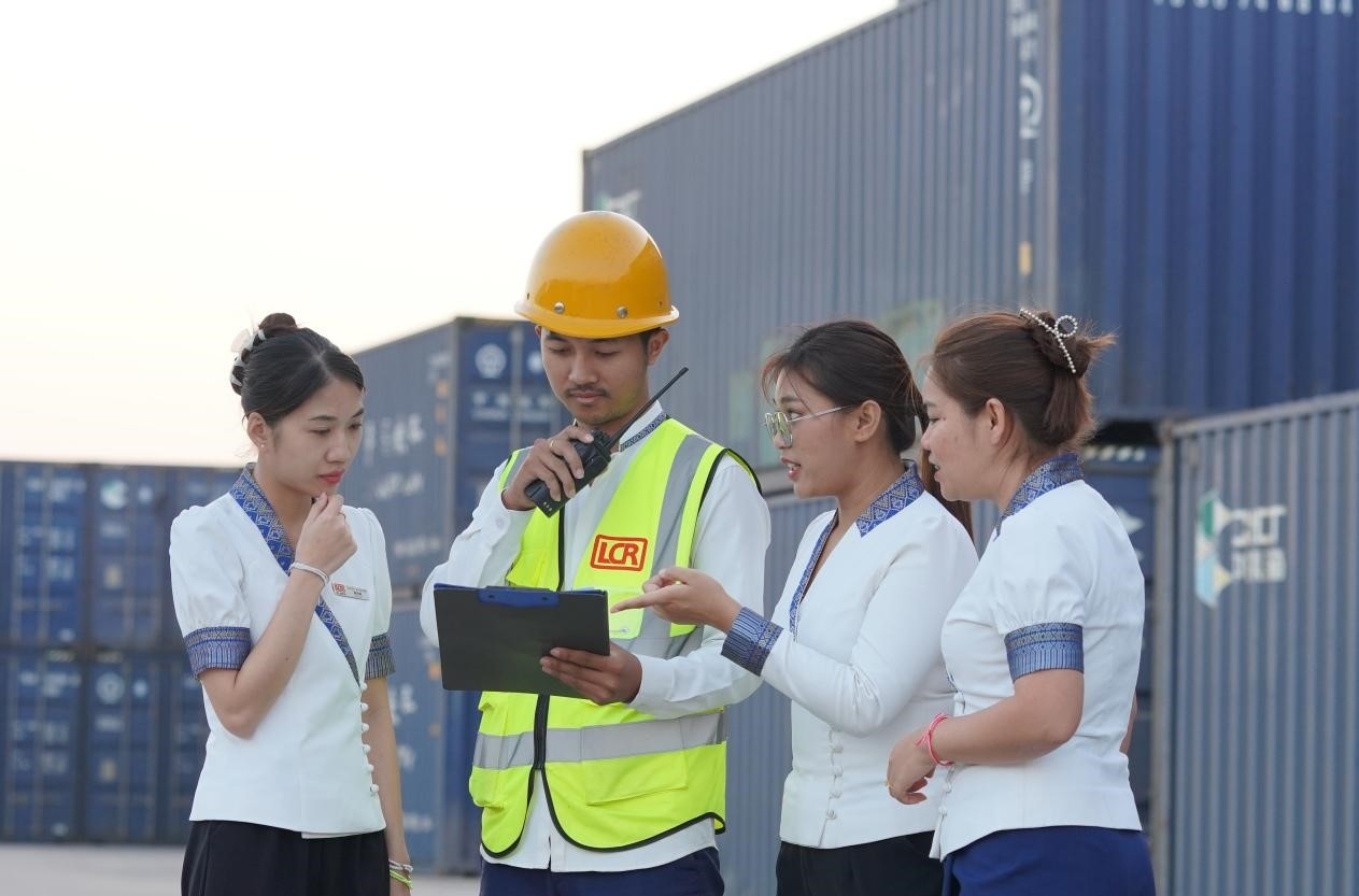 萬象南站貨運值班員陳尼啦（左一）與同事在一起討論工作。老中鐵路有限公司供圖