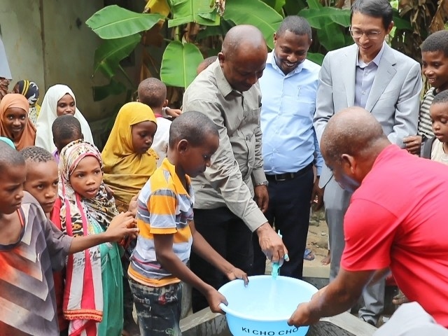 在日前舉行的安全供水工程揭牌儀式上，當(dāng)?shù)匦∨笥言诠┧c接水。 施亮攝