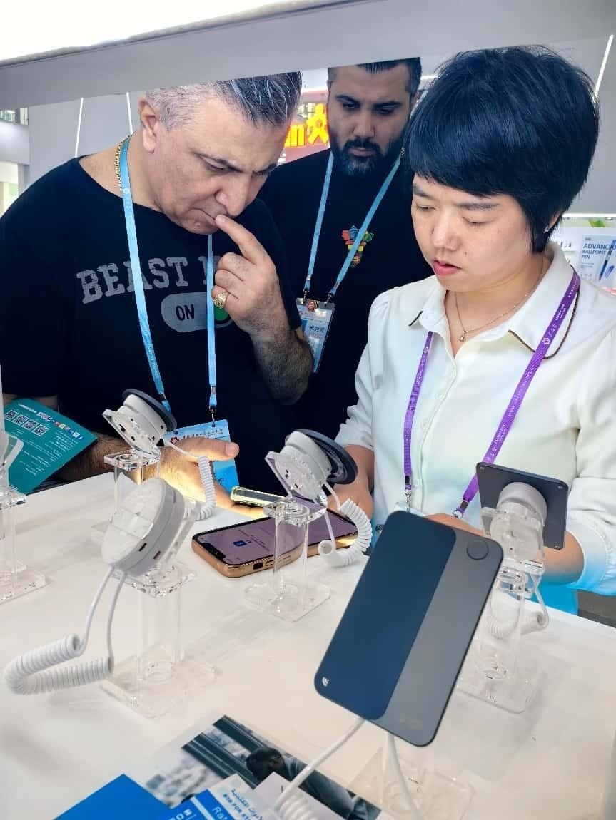 展臺工作人員向外商展示“AI TOP翻譯終端”。圖片來源：受訪者提供